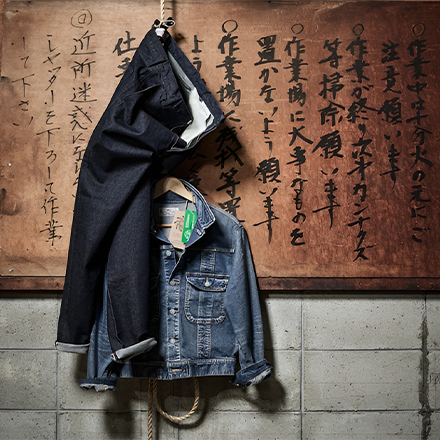 Denim trousers and denim jacket hanging in front of a wall with Japanese characters (Photo)