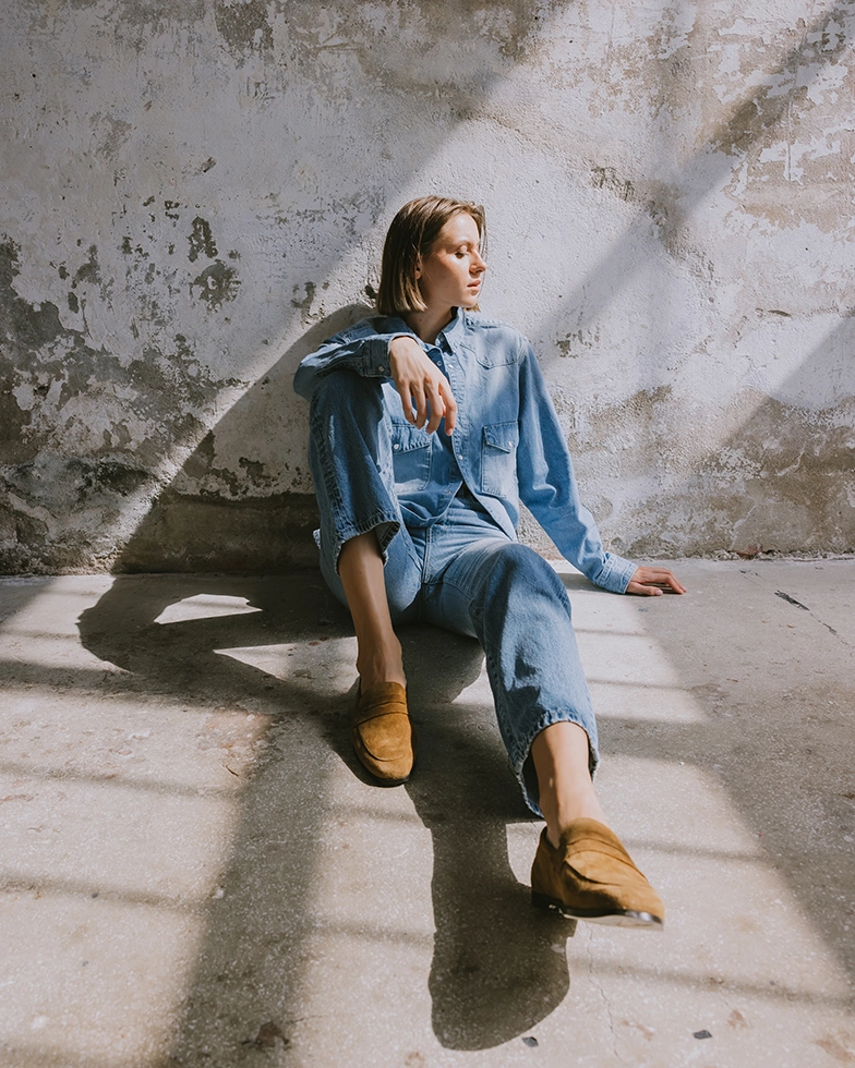 Woman in jeans sitting on the floor, looking into the distance (Photo)